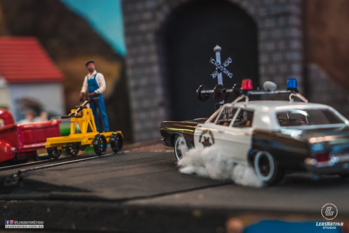 Miniature diorama of 70s with classic cars and trains.