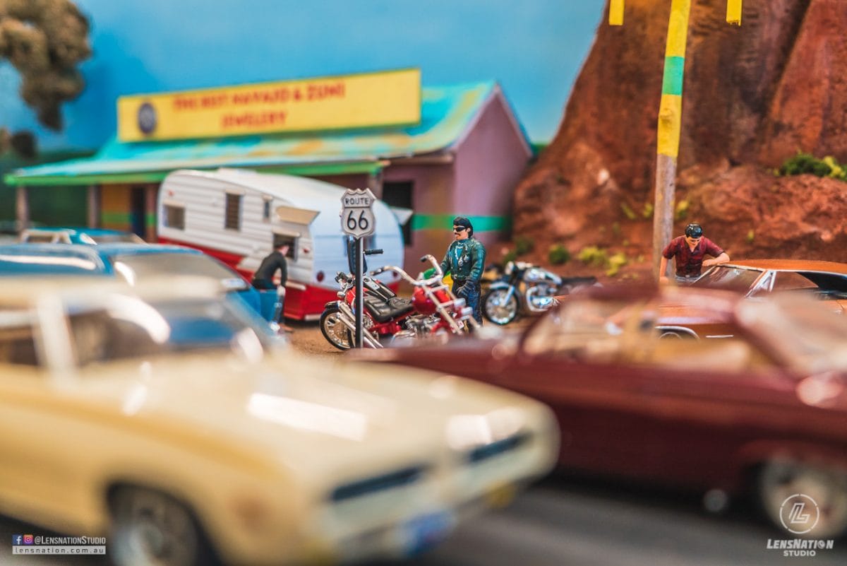 Miniature diorama of 70s with classic cars and trains.