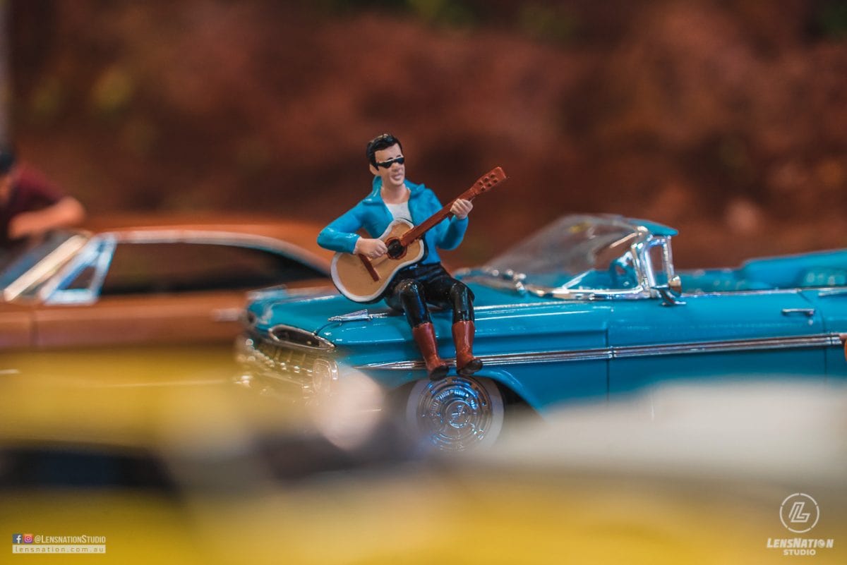 Miniature diorama of 70s with classic cars and trains.