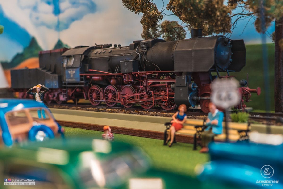 Miniature diorama of 70s with classic cars and trains.