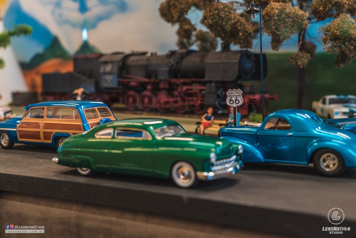 Miniature diorama of 70s with classic cars and trains.