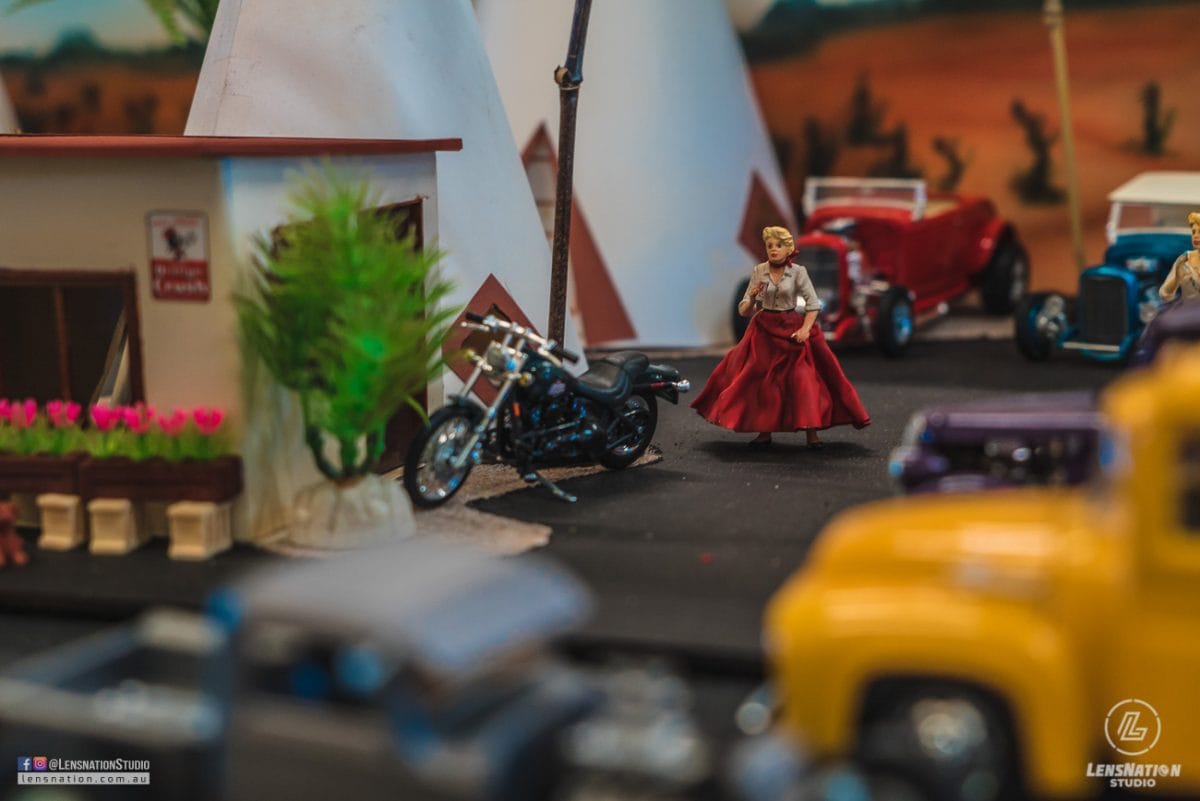 Miniature diorama of 70s with classic cars and trains.