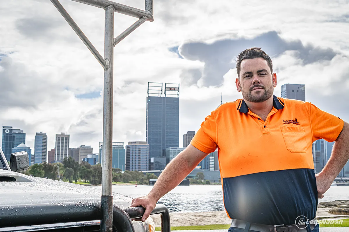 Close-up of branded plumbing vehicle with Perth skyline visible behind
