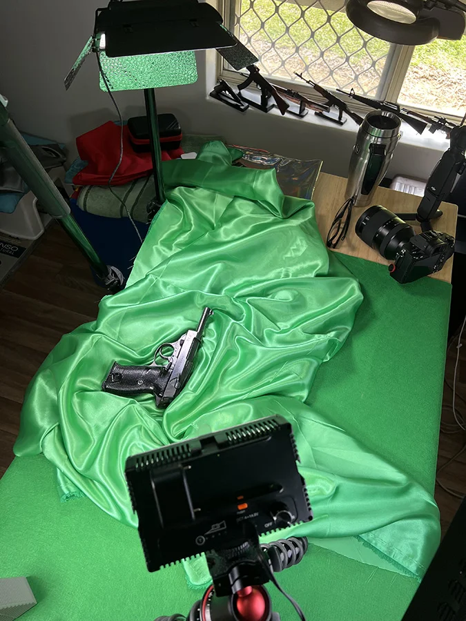 Initial setup of photographing a pistol on green reflective cloth background and light setup